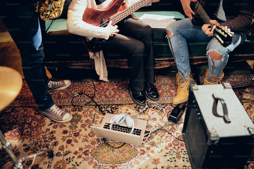 Musicians practicing for the gig in home studio. On the floor laptop and amplifier.