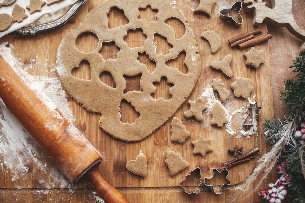 Making christmas gingerbread cookies flat lay. Dough with metal cutters on rustic table with wooden rolling pin, cinnamon ,anise, cones, christmas decorations. Atmospheric image