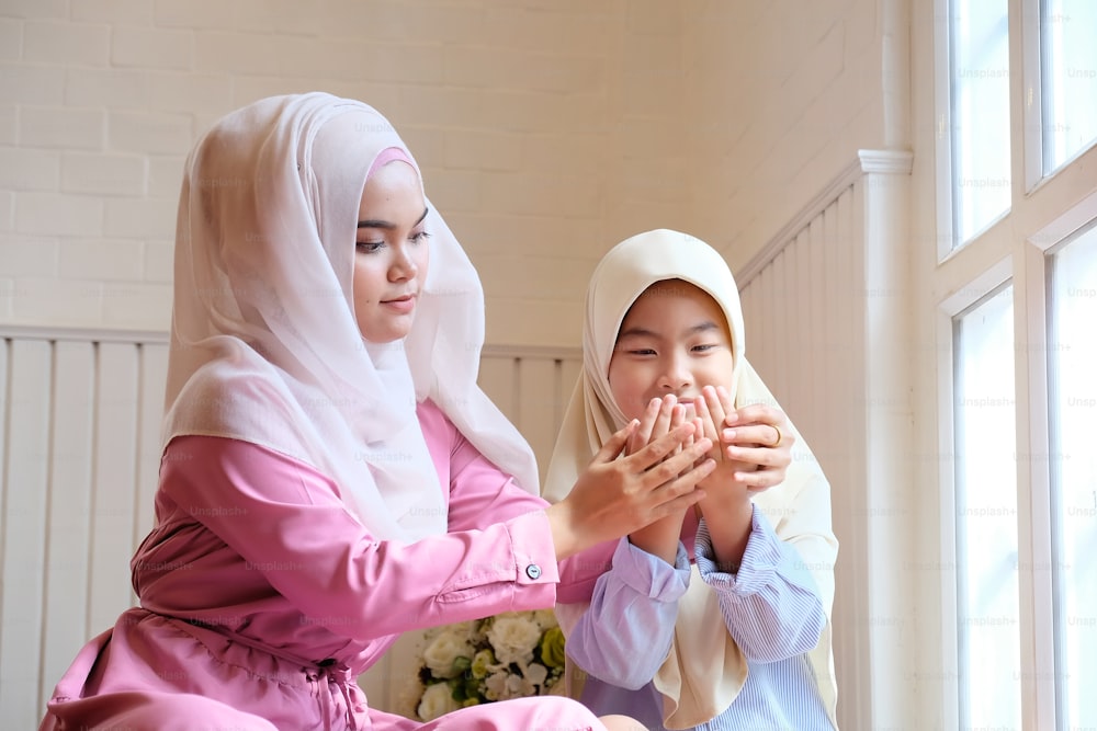 Children learning muslim praying with adult woman.