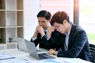 Stressed two businessman with laptop computer and documents at office.