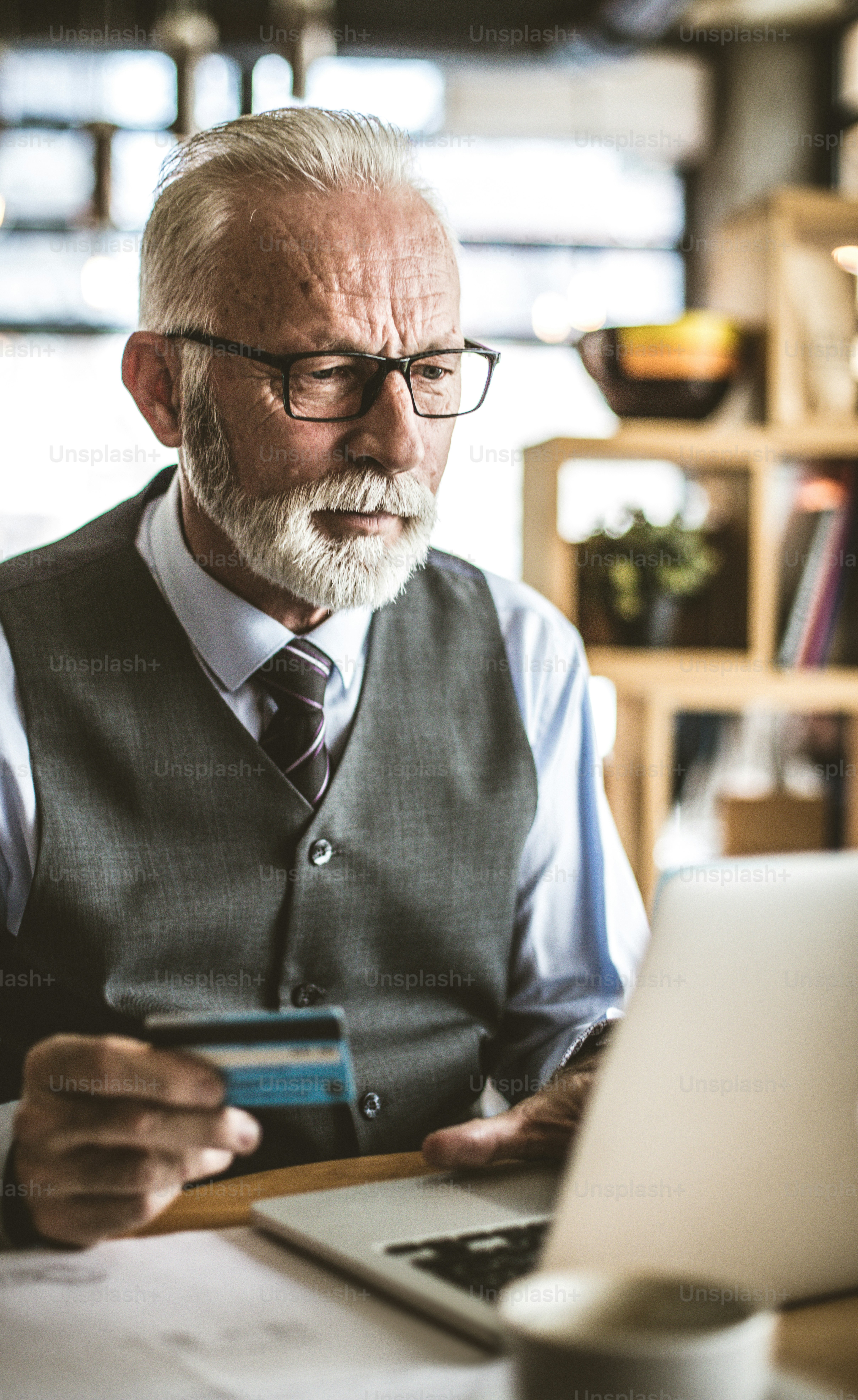 Control your account. Senior businessman using laptop to check credit card .