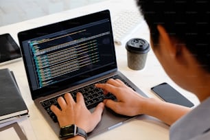 Um programador masculino que trabalha com laptop e codificação no computador.