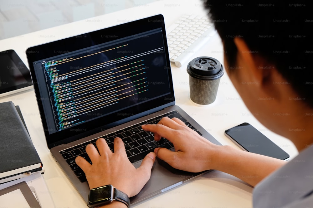 A male programer working with laptop and coding on computer.