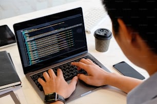 A male programer working with laptop and coding on computer.