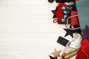Achats de Noël et soldes de saison. Cartes de crédit et argent dans un portefeuille, sacs en papier avec des vêtements, des bas, des étiquettes, des boîtes-cadeaux sur bois rustique. Remise spéciale de l’offre de Noël. Espace pour le texte
