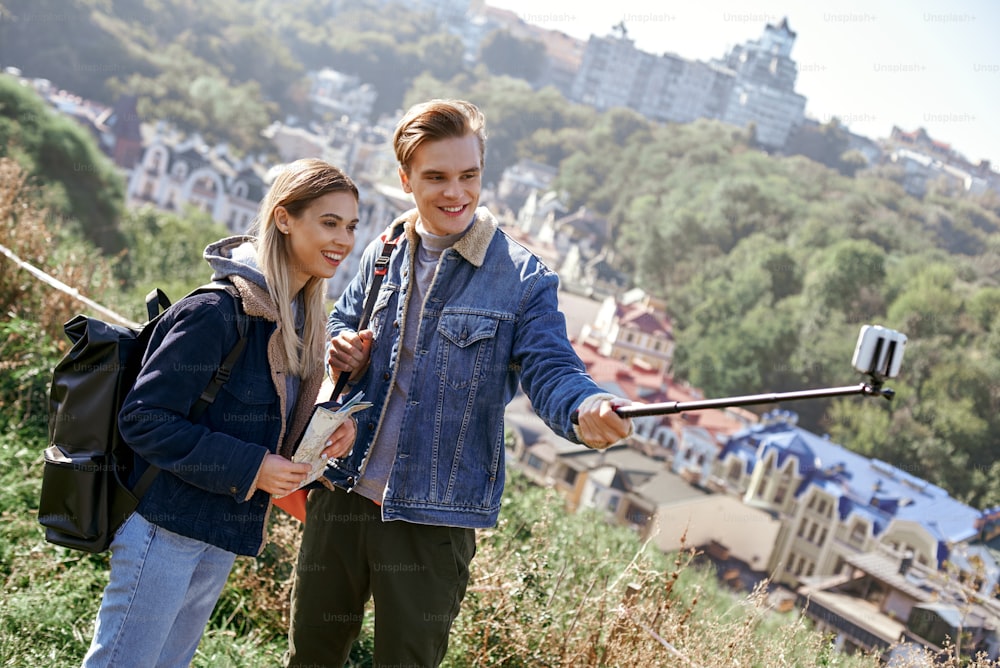 사랑에 빠진 행복한 젊은 부부는 언덕에서 셀카 사진을 찍는다. 예쁜 관광객은 유럽 여행 블로그에 대한 재미있는 사진을 만듭니다.