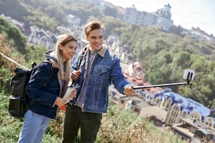Jovem casal feliz apaixonado tira selfie retrato em colinas. Turistas bonitos fazem fotos engraçadas para o blog de viagens na Europa.