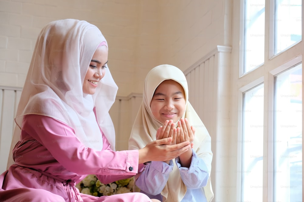 Children learning muslim praying with adult woman.