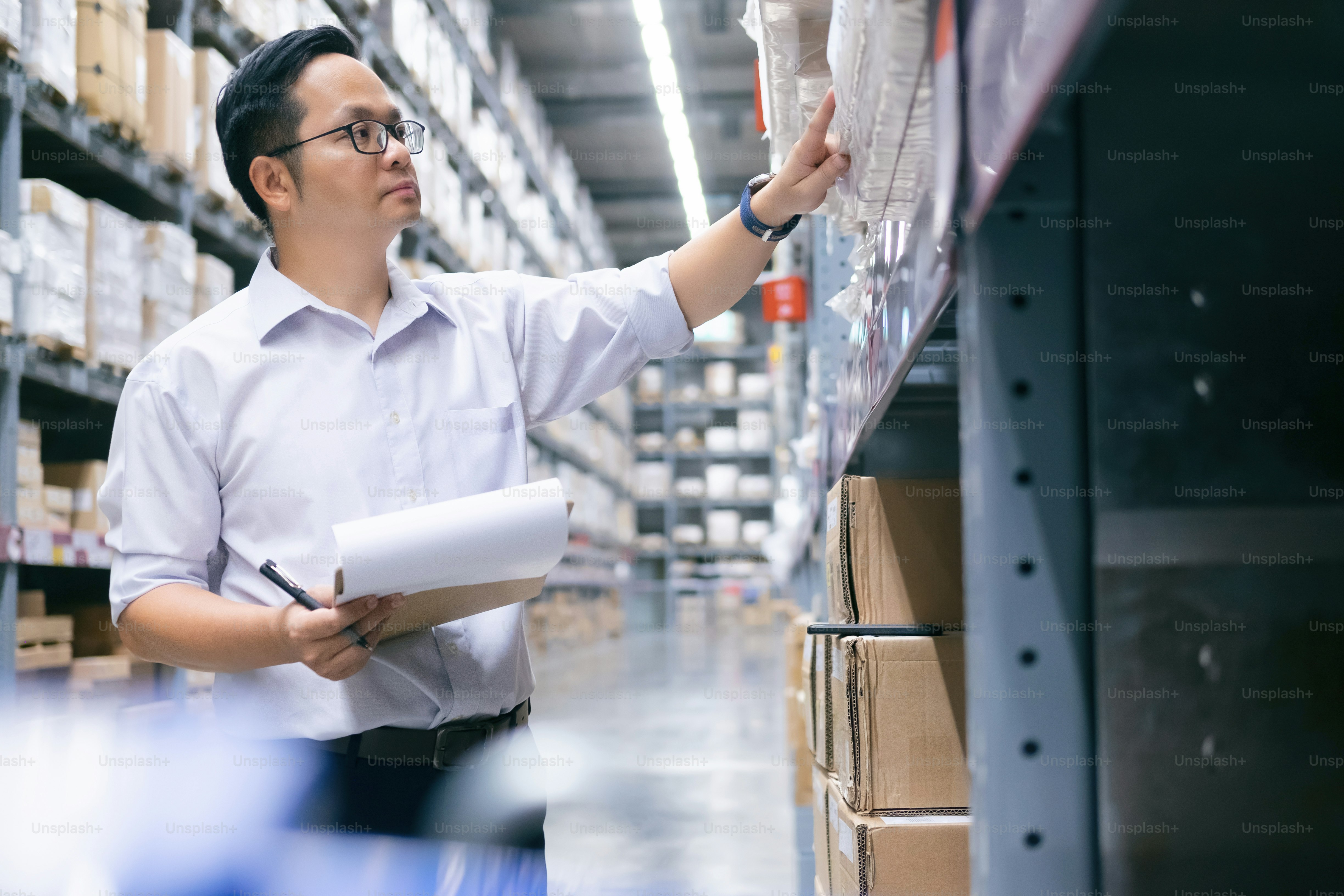 Commercio all'ingrosso, logistica, affari, esportazione e concetto di persone - Magazziniere uomo che controlla le merci in magazzino.