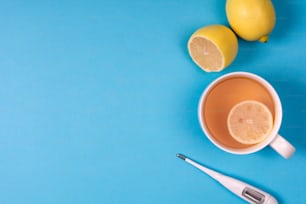 Termómetro médico electrónico, frasco de medicación con pastillas, spray para la nariz y té con limón sobre fondo azul. Concepto de cuidado de la salud. Fitoterapia y medicina química. Vista superior. Espacio de copia. Tendido plano