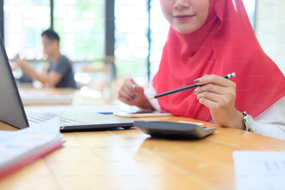 Islam femenino trabajando con finanzas y calcular finanzas en calculadora.