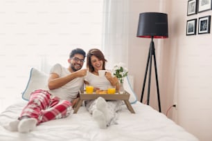 사랑에 빠진 행복한 커플은 침대에 누워 아침을 먹고 함께 시간을 즐기며 모닝 커피를 마신다