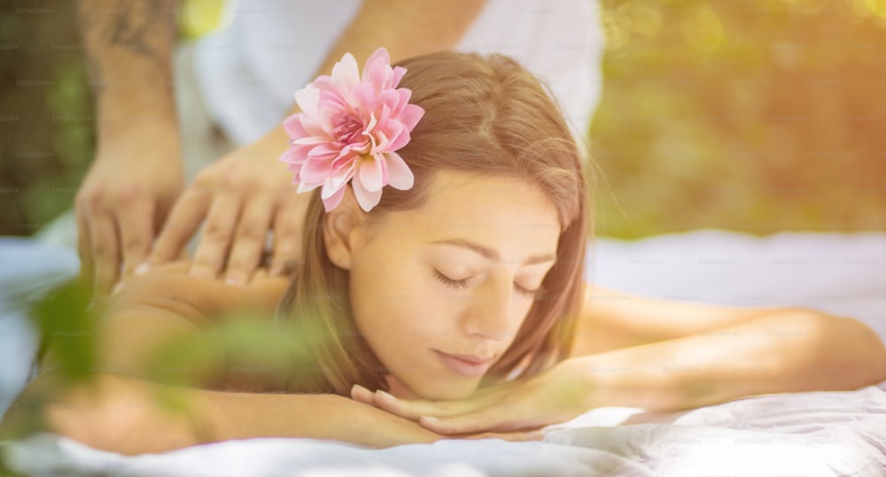 Give her the best treatment. Close up image of young woman at massage treatment.  In nature.