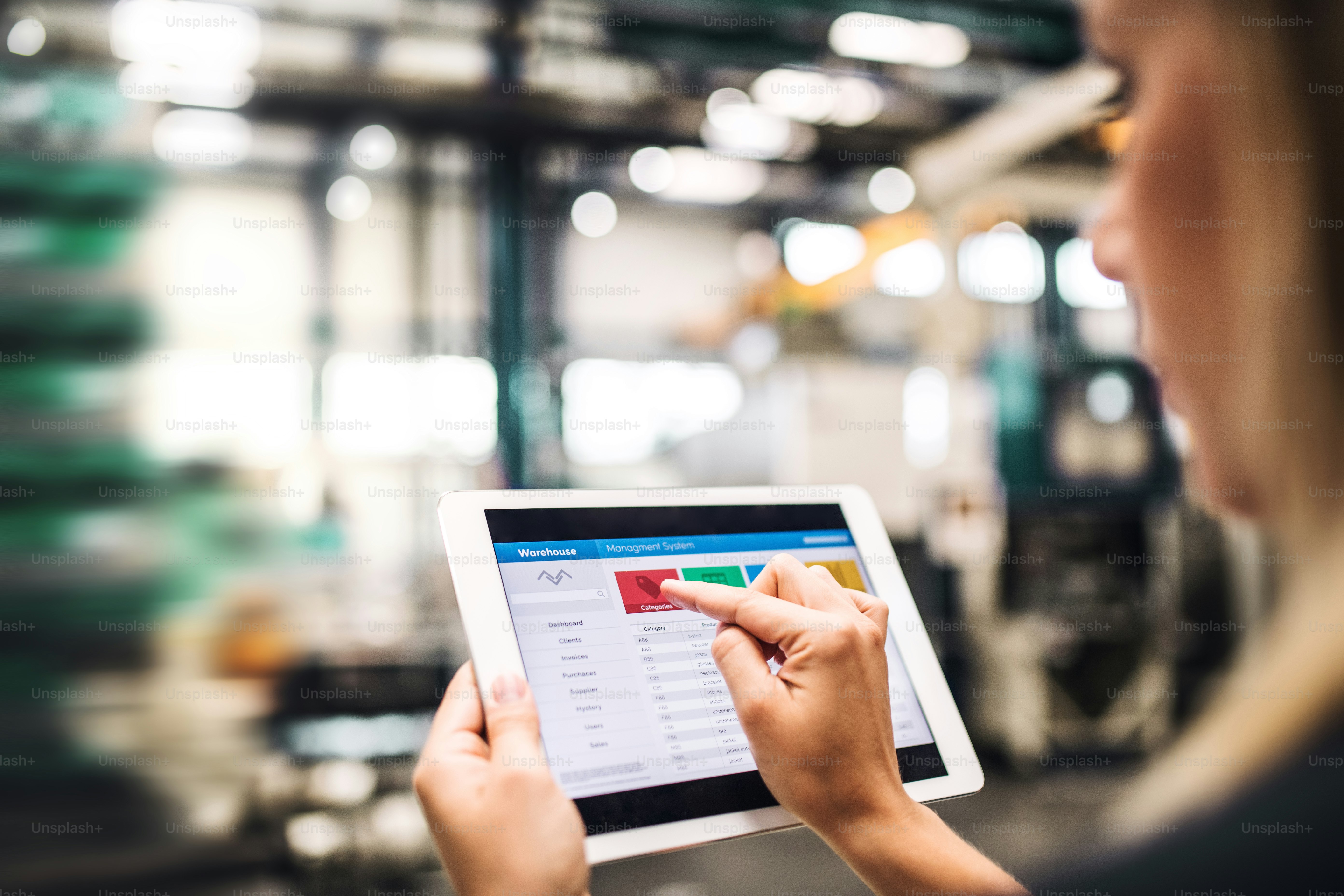 Une ingénieure industrielle méconnaissable dans une usine utilisant une tablette.