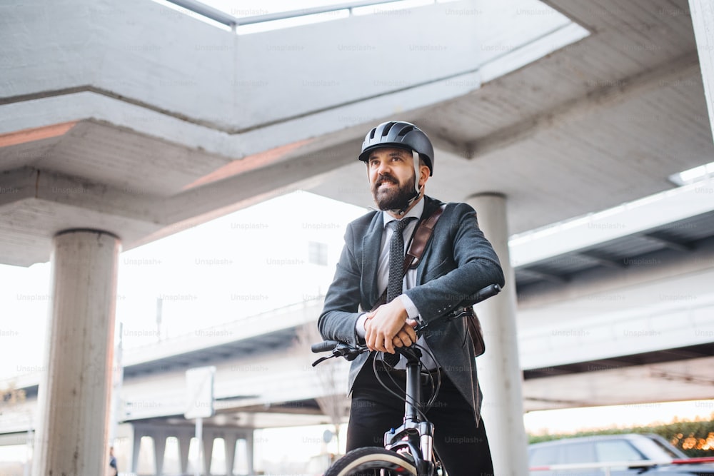 Empresário hipster com bicicleta elétrica viajando para casa do trabalho na cidade ao pôr do sol. Espaço de cópia.
