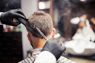 Una vista trasera del cliente del hombre que visita a la peluquería y al peluquero en la peluquería.