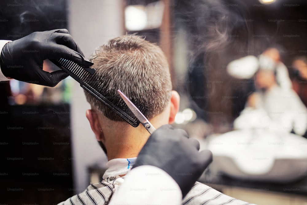 Uma visão traseira do cliente do homem visitando haidresser e cabeleireiro na barbearia.