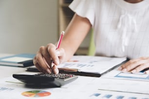 Close up Business woman using calculator and laptop for do math finance on wooden desk in office and business working background, tax, accounting, statistics and analytic research concept