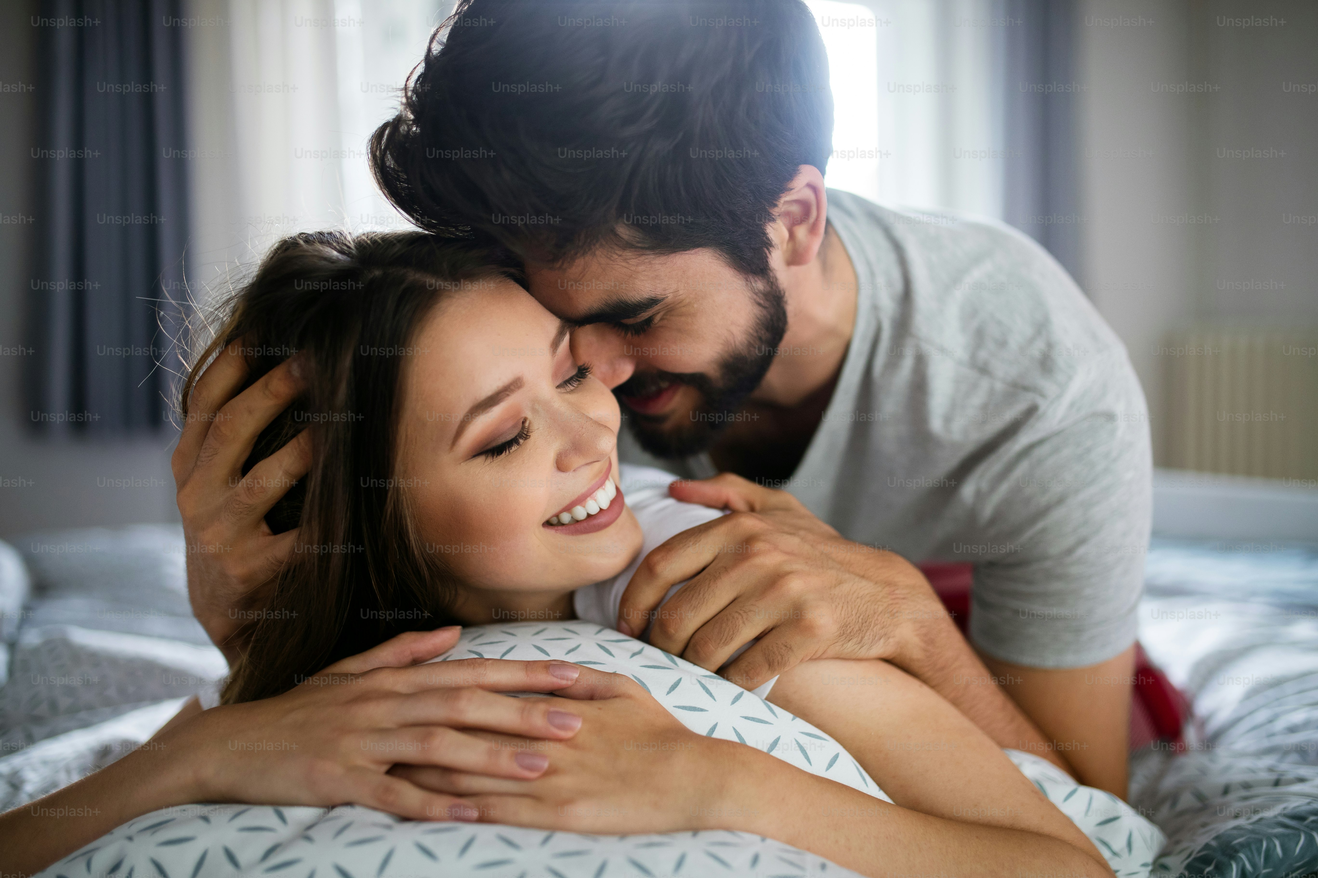 Beautiful couple of young lovers are hugging indoors at home, with love and tenderness