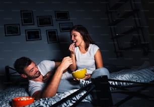 La giovane coppia si diverte a guardare la televisione la sera in pigiama.