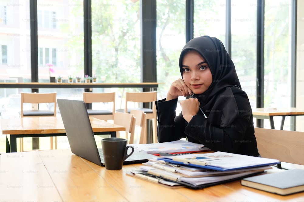 Islamische Frau arbeitet im Café mit Porträtaufnahme auf dem Tisch. Konzept der berufstätigen Frau.