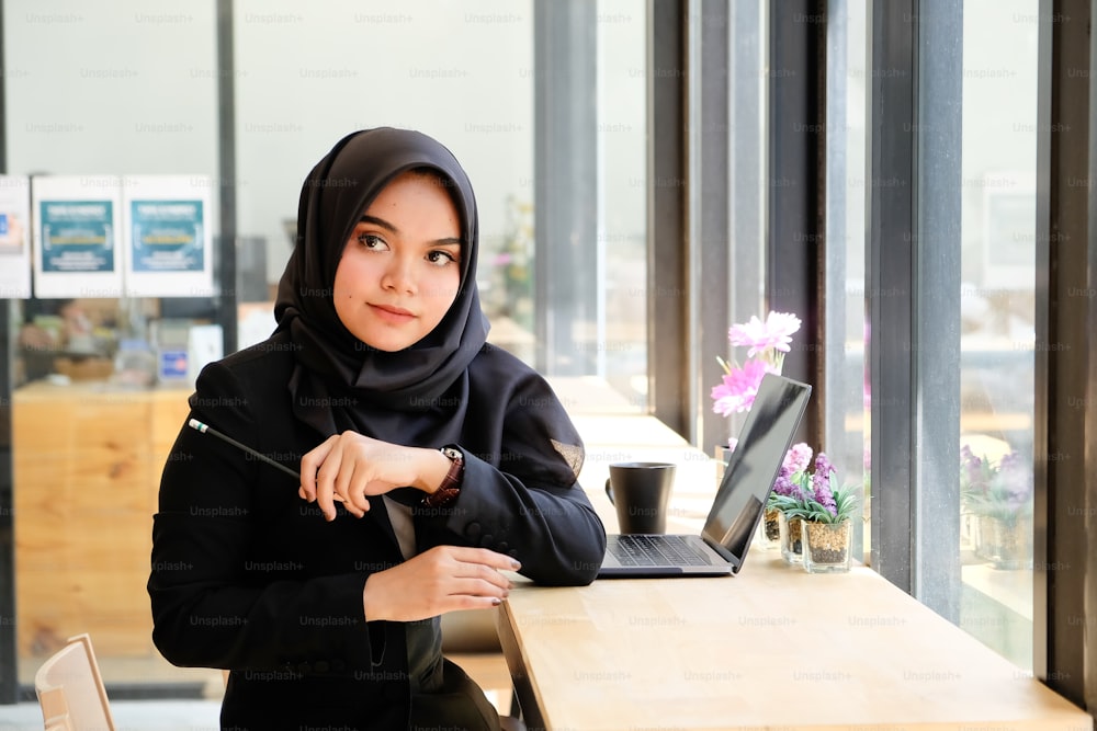 Konzept der arbeitenden Frau, islamische Frau bei der Arbeit im Café mit Porträtaufnahme auf dem Tisch.