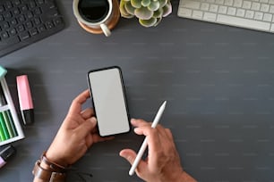 Graphic designer holding mobile smart phone on studio top table