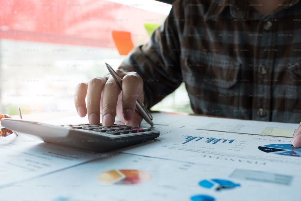 Hombre calculando el impuesto sobre la renta individual a partir de un documento financiero con calculadora en su oficina - Concepto financiero empresarial