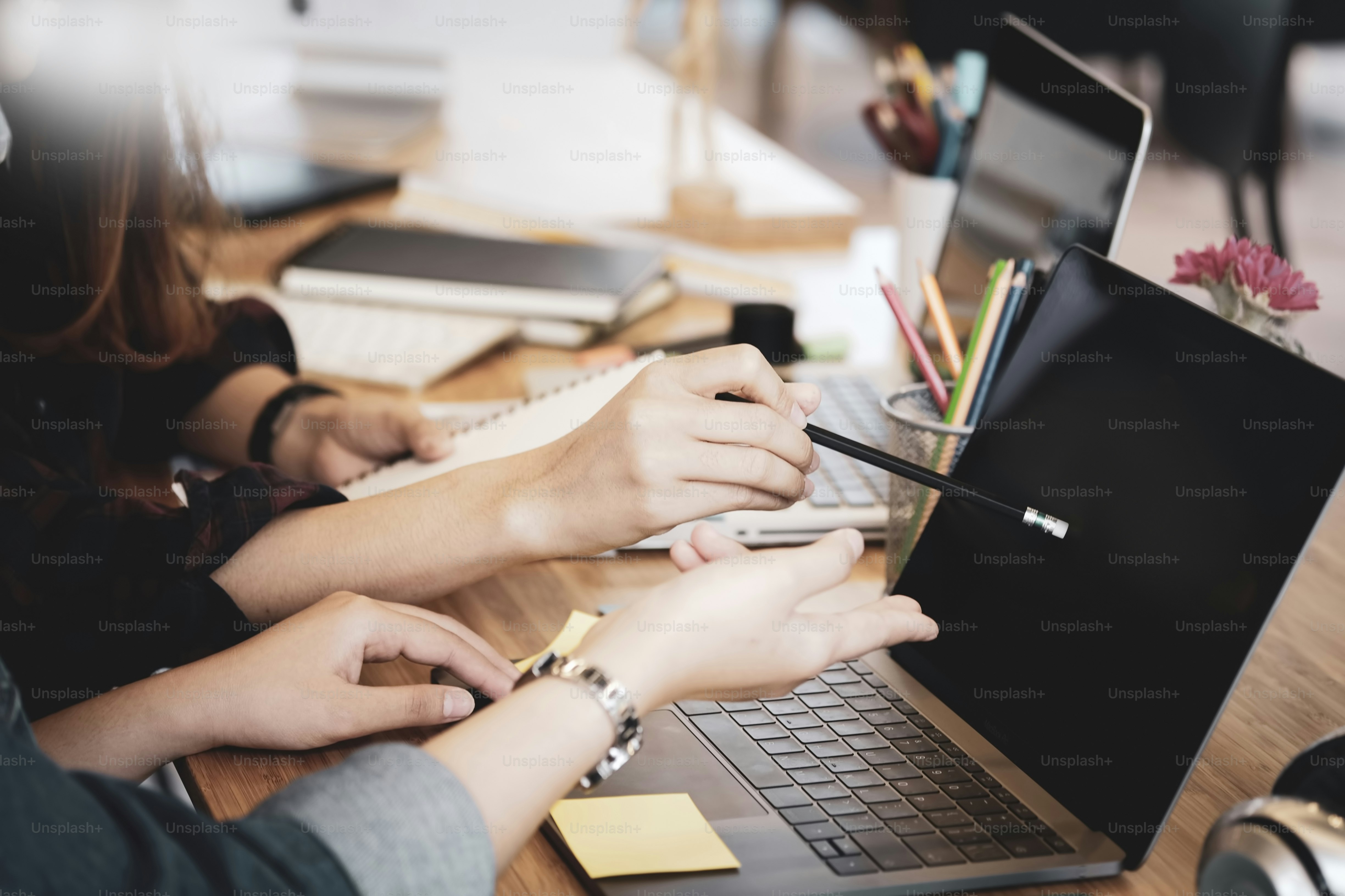 Geschäftskollegen diskutieren über die Arbeit, während sie am Arbeitsplatz mit Daten auf dem Laptop sitzen
