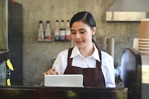 Femmes asiatiques Barista souriant et utilisant une tablette pour prendre la commande dans le comptoir du café