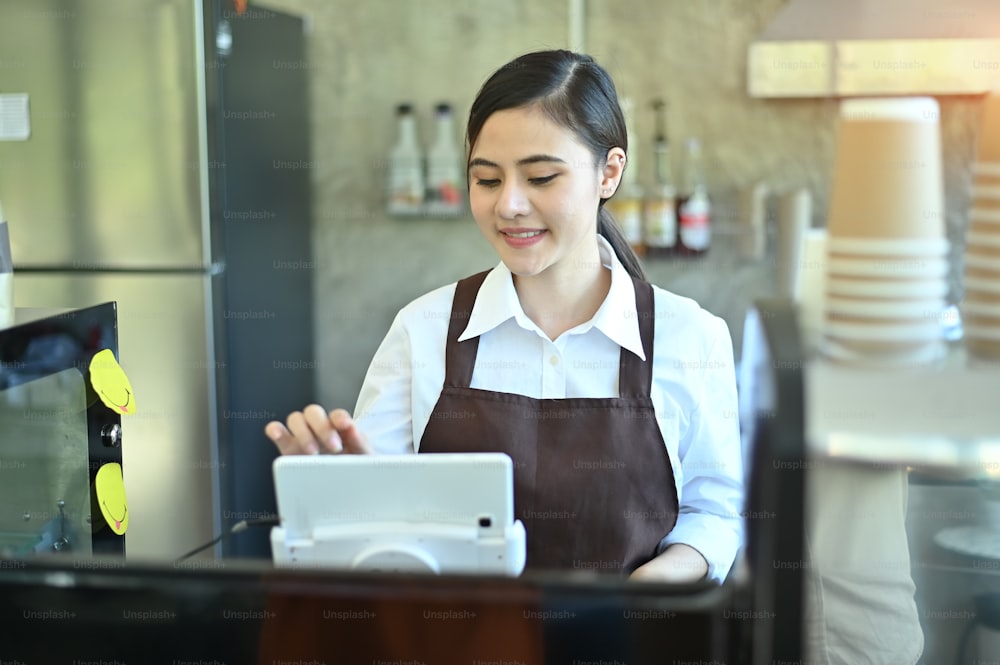 Cropped shot barista using mobile ordering Kitchen System with digital tablet.
