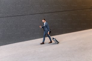 Young man on business trip walking with his luggage at airport.
