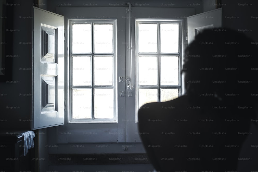 Femme silhouette nue regardant par une fenêtre vintage.