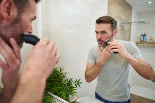 Homem maduro com barbear elétrico na casa de banho