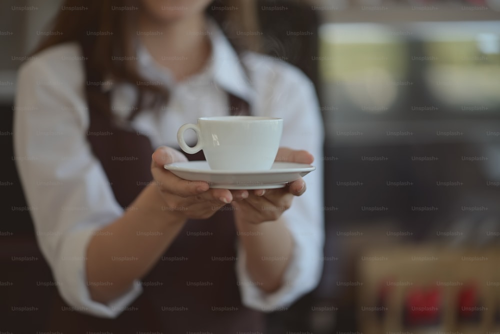Barista in apron holding coffee for serving in coffee shop