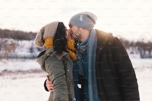 Mulher e homem felizes, beijando e abraçando, passando tempo juntos se encantando, neve, vida, inverno. Retrato maravilhoso jovem casal usando chapéus de lã elegantes e cachecóis.