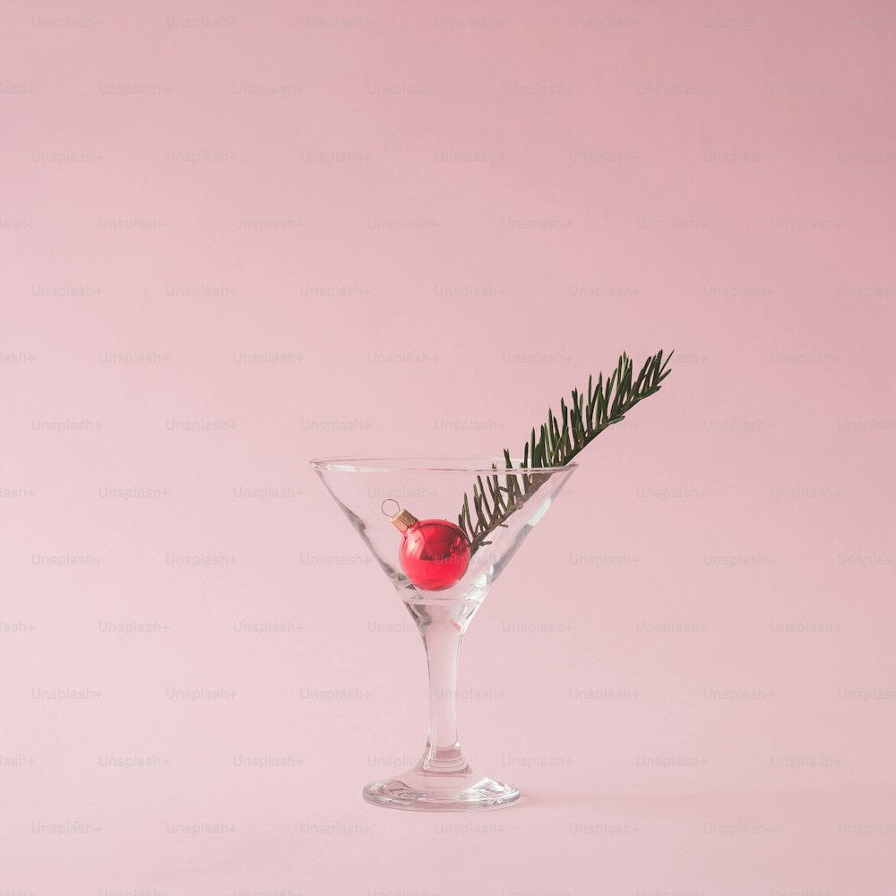 Christmas tree decoration in martini glass on pastel pink background with creative copy space.