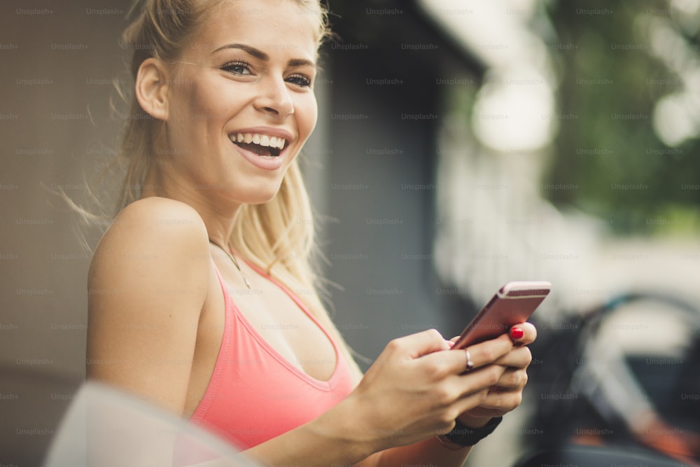 Faites une pause pour envoyer des messages à vos amis. Jeunes femmes sportives souriantes heureuses utilisant un téléphone intelligent. Portrait.