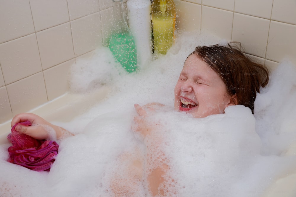 Little child taking a bath playing with foam baby girl having soapy bath at home