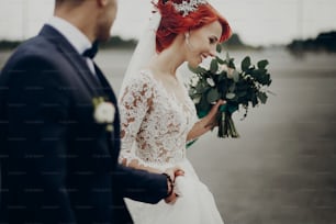 stylish bride and groom walking and smiling,  with boho bouquet. luxury wedding couple newlyweds, happy emotional moment. space for text. modern couple with true feelings