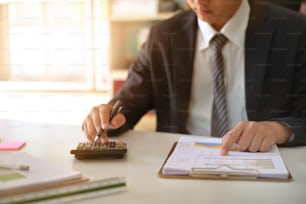 Homme d’affaires faisant des finances et calculant sur le bureau sur le coût au bureau à domicile.