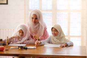 concepto de educación musulmana, enseñanza femenina adulta con arte para aprender a una niña de dos niños en el hogar con el lugar de trabajo del artista.