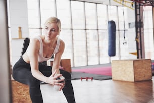 Foto da mulher fitness atraente no ginásio segurando garrafa de água.
