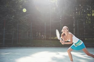Süßes Mädchen, das Tennis spielt und für die Kamera posiert