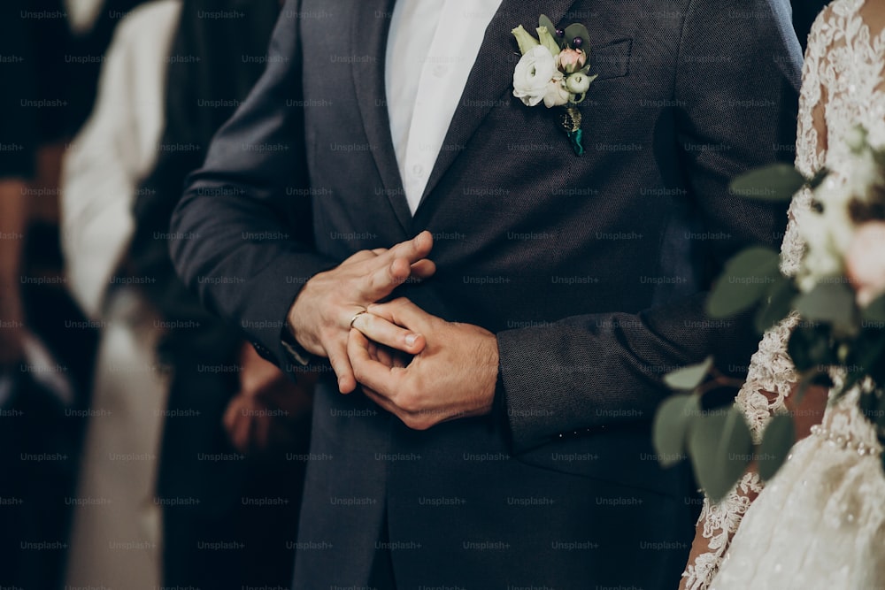 pareja de novios poniéndose anillos de boda en el matrimonio en la iglesia. Novia y novio con estilo besándose e intercambiando anillos. momento emotivo, espacio para el texto. Concepto de religión