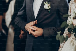 wedding couple putting on wedding rings at matrimony in church. stylish bride and groom kissing and exchanging rings. emotional moment, space for text. religion concept