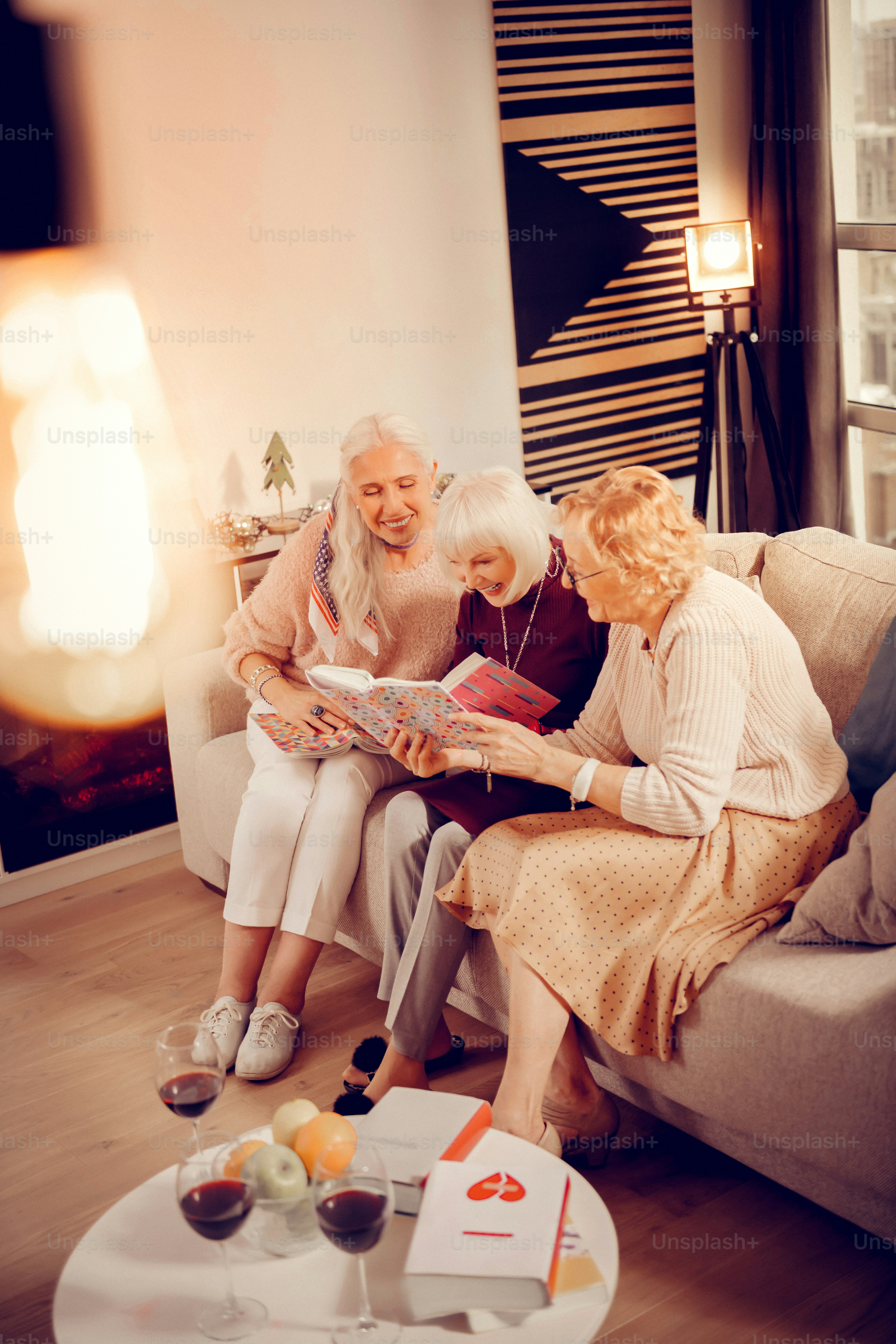C’est tellement amusant. Des femmes joyeuses et positives regardant le livre lors d’une réunion de club de lecture