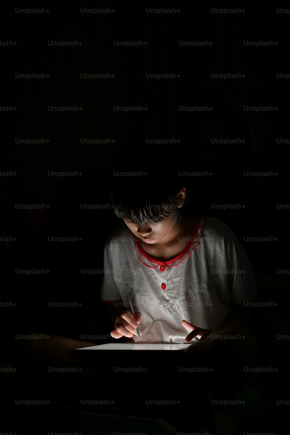 Adolescente asiática usando el dibujo de la tableta mientras está acostada en la cama