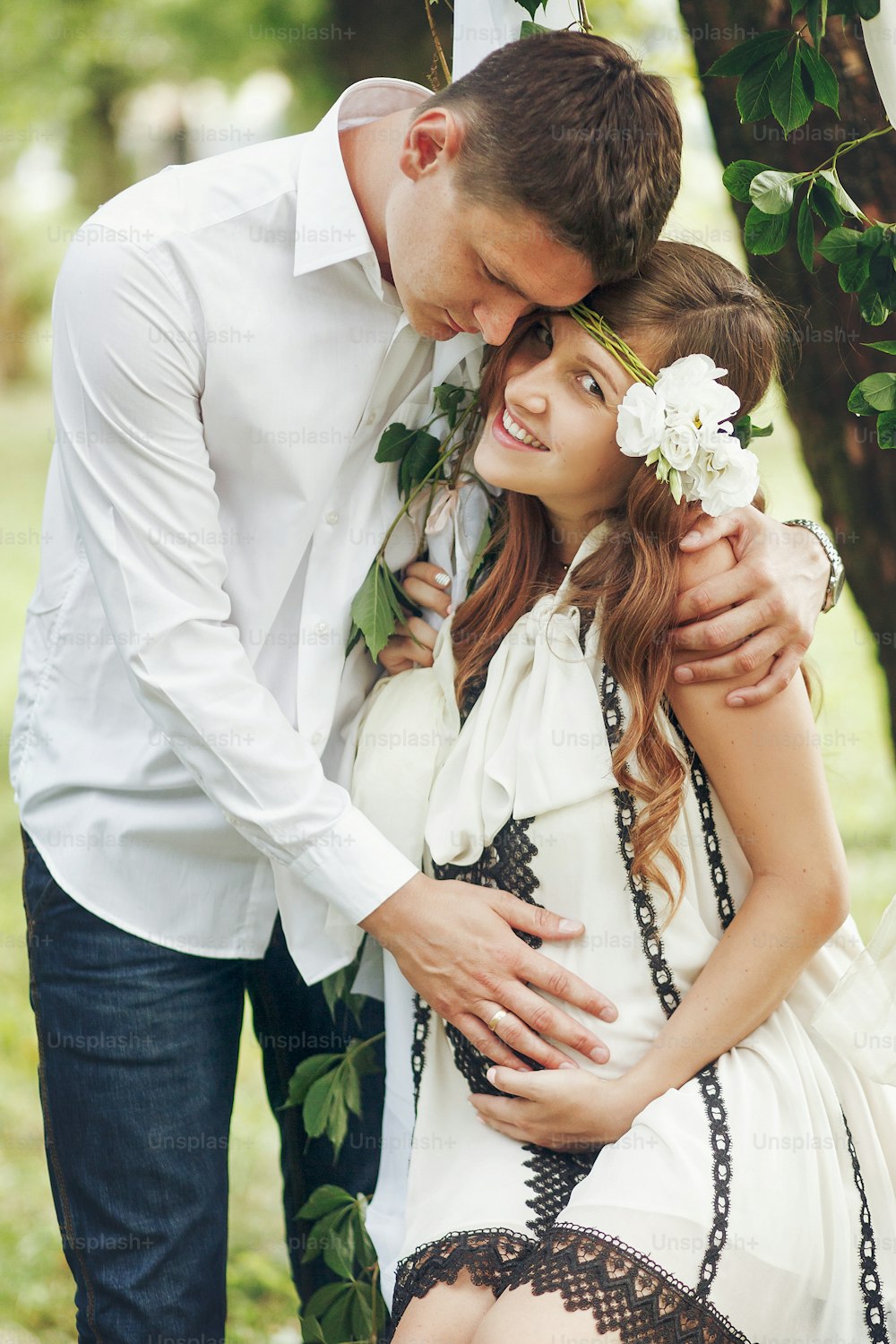 Happy beautiful family couple, handsome man and pregnant woman in vintage dress hugging near swing