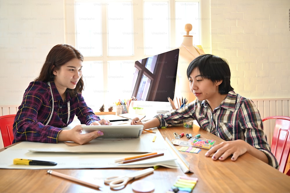 デジタルタブレットで作業するデザイナーの会議は、職場でファッションをデザインします。
